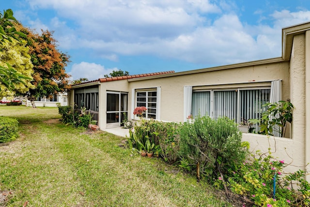 back of property featuring a sunroom and a lawn