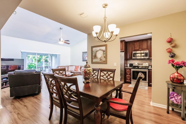 dining space featuring light wood-type flooring, ceiling fan with notable chandelier, and vaulted ceiling