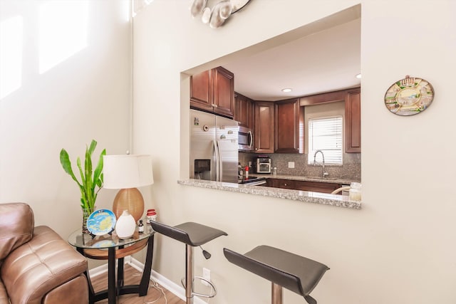 kitchen featuring light stone countertops, kitchen peninsula, appliances with stainless steel finishes, and sink