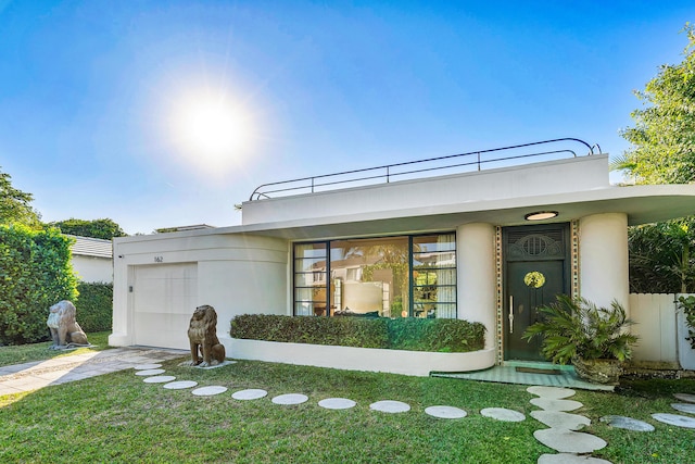 art deco inspired home featuring a garage and a front lawn