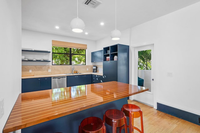 kitchen with pendant lighting, dishwasher, butcher block counters, sink, and backsplash