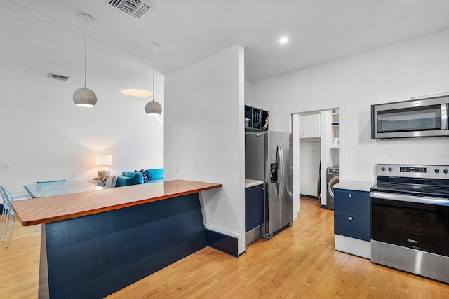 kitchen with kitchen peninsula, washer / dryer, decorative light fixtures, white cabinets, and stainless steel appliances