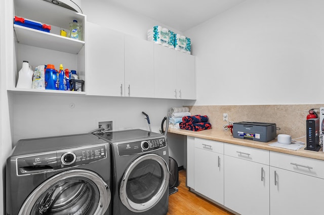 clothes washing area featuring cabinets, separate washer and dryer, and light wood-type flooring