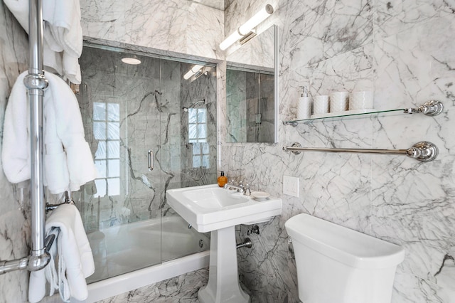 bathroom with toilet, shower / bath combination with glass door, and tile walls