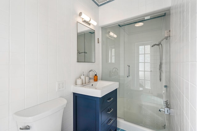 bathroom with vanity, toilet, tile walls, and a shower with door