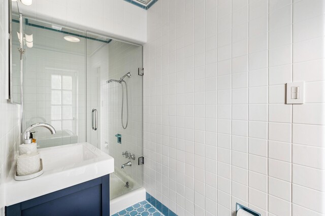 bathroom with tile walls, tile patterned floors, vanity, and tiled shower / bath