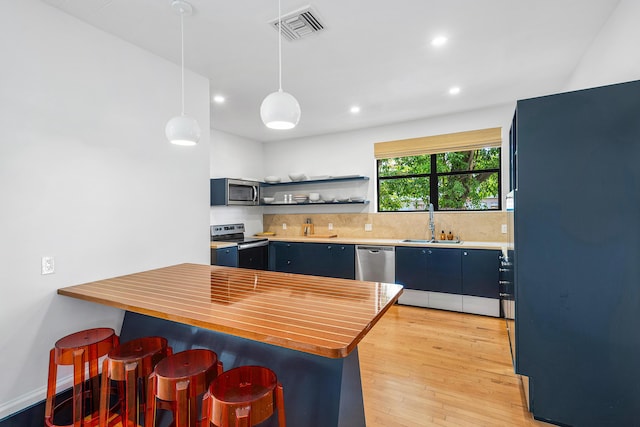 kitchen featuring decorative light fixtures, sink, decorative backsplash, a breakfast bar area, and stainless steel appliances