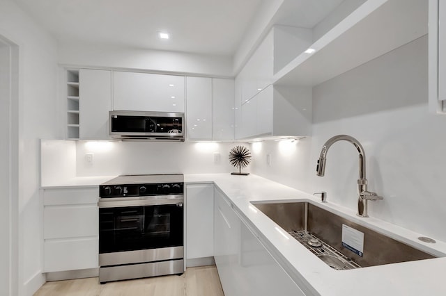 kitchen featuring sink, white cabinets, light hardwood / wood-style floors, and electric stove