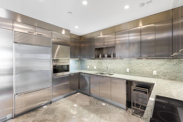 kitchen with sink, tasteful backsplash, light stone countertops, and stainless steel appliances