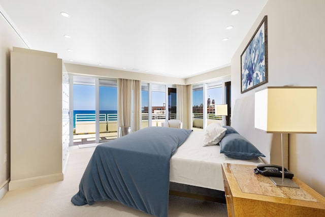 carpeted bedroom with access to exterior and a water view