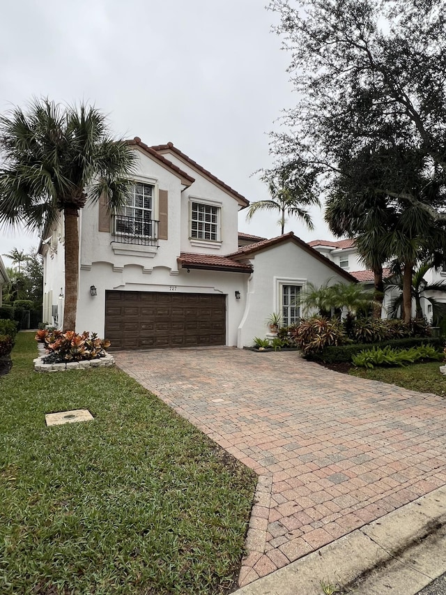 mediterranean / spanish house featuring a garage and a front lawn