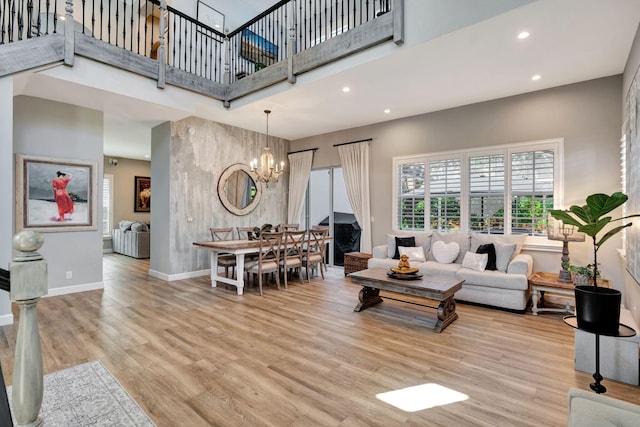 living room with an inviting chandelier, a high ceiling, and light wood-type flooring