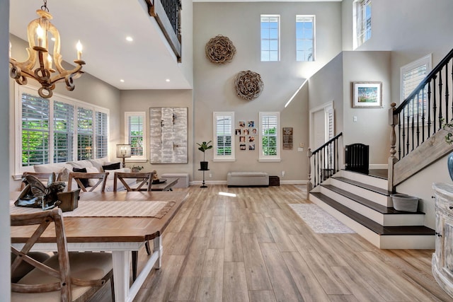 entrance foyer featuring a notable chandelier, plenty of natural light, light hardwood / wood-style floors, and a high ceiling