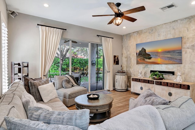 living room featuring ceiling fan, a fireplace, and light hardwood / wood-style flooring