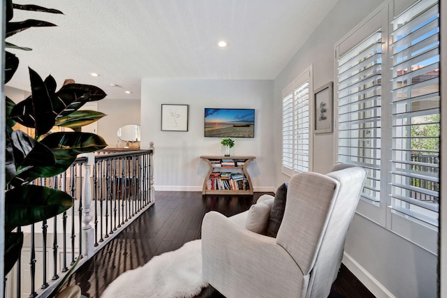 sitting room with dark wood-type flooring and a wealth of natural light