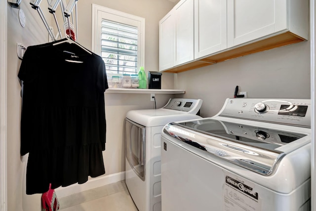 clothes washing area with independent washer and dryer, light tile patterned floors, and cabinets