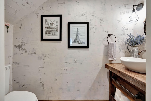 bathroom featuring vanity, lofted ceiling, and toilet