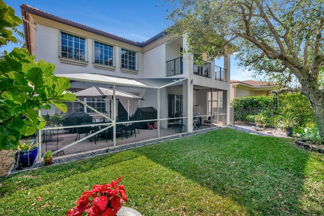 rear view of house featuring a balcony, a patio area, and a lawn