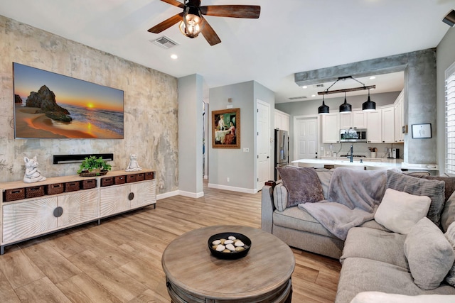 living room with ceiling fan and light hardwood / wood-style flooring