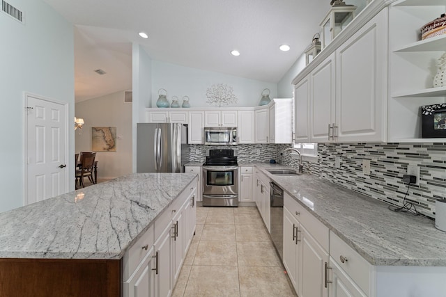 kitchen featuring appliances with stainless steel finishes, white cabinetry, sink, vaulted ceiling, and light stone counters