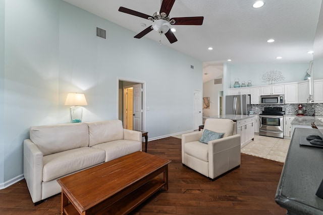 living room featuring ceiling fan, high vaulted ceiling, and dark hardwood / wood-style floors