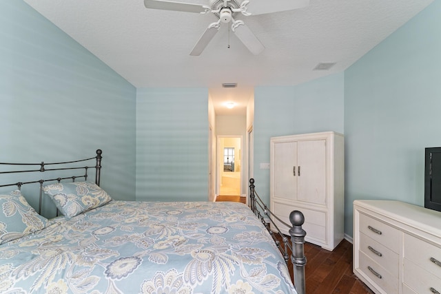 bedroom with a textured ceiling, ceiling fan, and dark hardwood / wood-style flooring