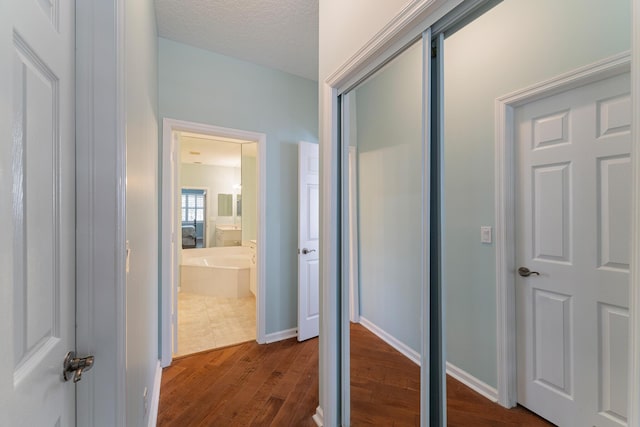hallway with a textured ceiling and dark hardwood / wood-style flooring