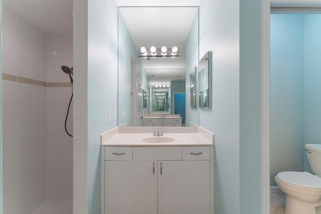 bathroom featuring a tile shower, toilet, and vanity