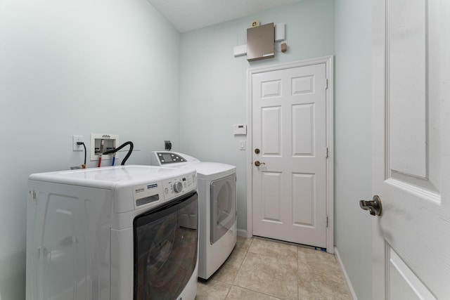 laundry room featuring washing machine and dryer and light tile patterned floors