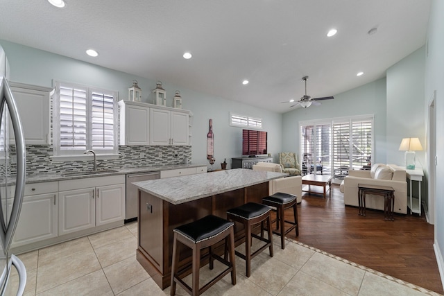 kitchen featuring a center island, appliances with stainless steel finishes, light tile patterned floors, white cabinets, and sink