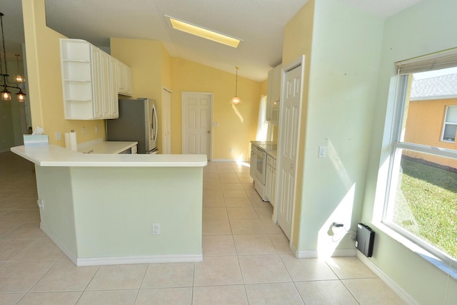 kitchen featuring lofted ceiling, stainless steel refrigerator, hanging light fixtures, light tile patterned flooring, and kitchen peninsula