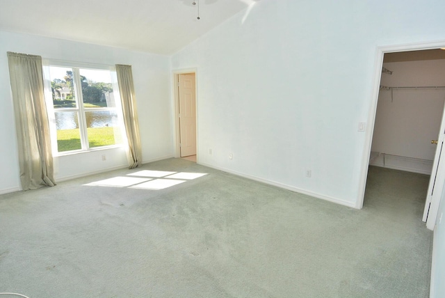 carpeted spare room with a water view and lofted ceiling