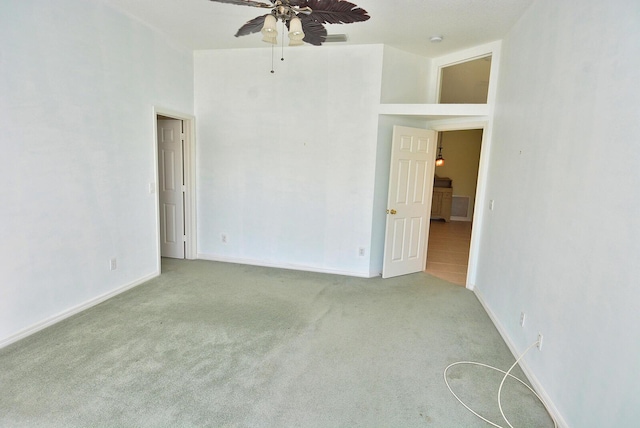 spare room featuring light colored carpet, ceiling fan, and a high ceiling