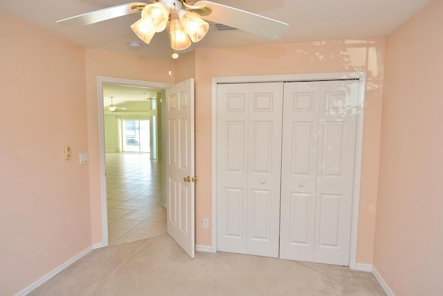 unfurnished bedroom featuring light colored carpet, a closet, and ceiling fan