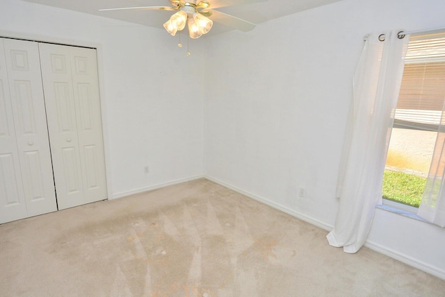 unfurnished bedroom featuring ceiling fan, a closet, and light carpet