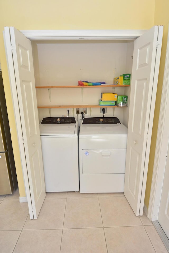 laundry area with washer and dryer and light tile patterned floors