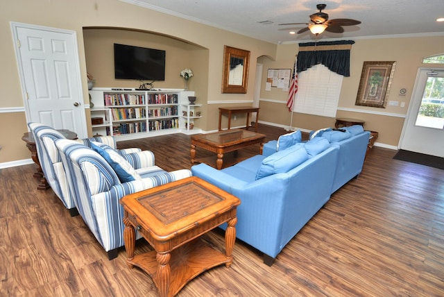 living room with dark wood-type flooring, ornamental molding, and ceiling fan