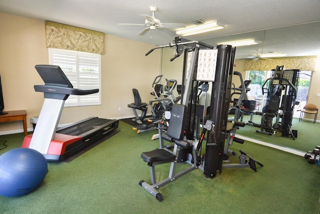 gym featuring ceiling fan, a healthy amount of sunlight, and a textured ceiling