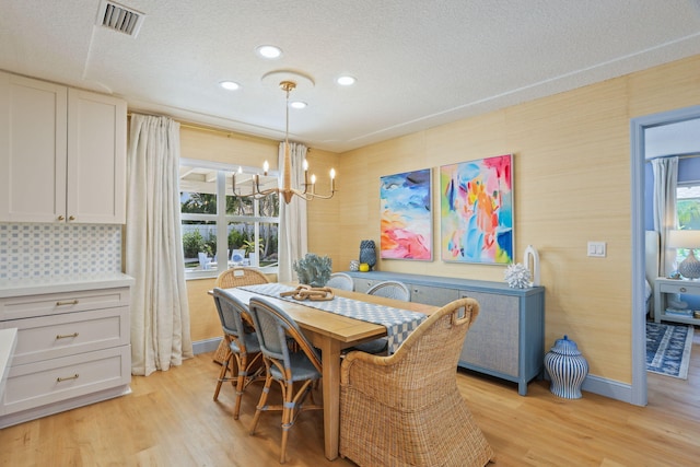 dining space featuring a notable chandelier, a healthy amount of sunlight, and light hardwood / wood-style flooring