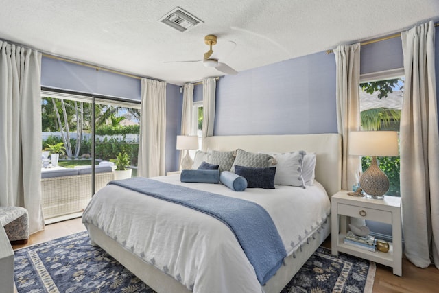 bedroom featuring ceiling fan, access to outside, a textured ceiling, and hardwood / wood-style flooring