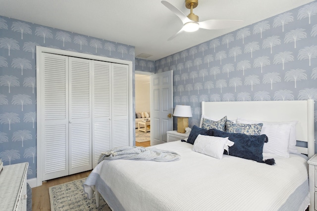 bedroom with ceiling fan, wood-type flooring, and a closet