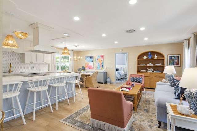 living room with sink, a notable chandelier, and light hardwood / wood-style floors