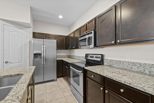 kitchen featuring sink, appliances with stainless steel finishes, dark brown cabinetry, light stone countertops, and light tile patterned flooring