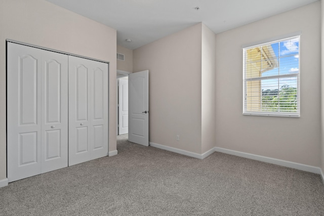 unfurnished bedroom with light carpet and a closet