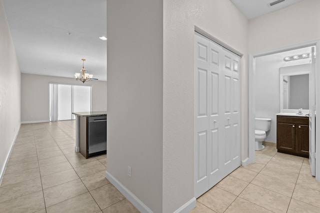 hall featuring light tile patterned flooring, sink, and a chandelier