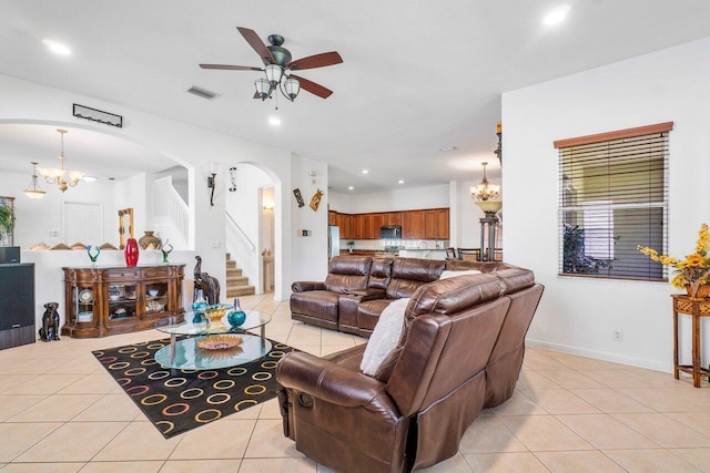 tiled living room with ceiling fan with notable chandelier