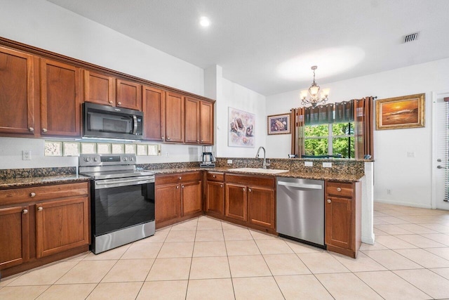 kitchen with sink, dark stone counters, light tile patterned floors, a notable chandelier, and stainless steel appliances