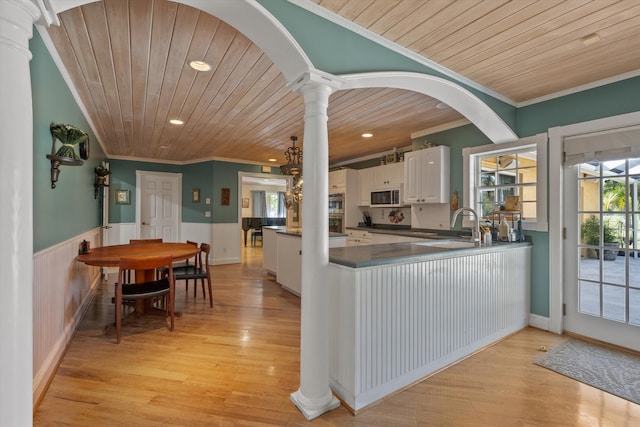 kitchen with decorative columns, white cabinetry, wooden ceiling, and crown molding