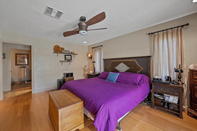 bedroom featuring a textured ceiling, ceiling fan, and light hardwood / wood-style flooring