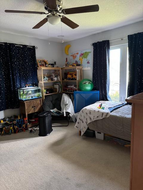 bedroom featuring ceiling fan, a textured ceiling, and carpet flooring